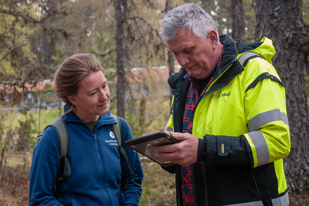 Maria Knagenhjelm og Jan Ivar Rødland ser på miljøregistreringer i skogen ved hjelp av programmet ALLMA på en ipad.